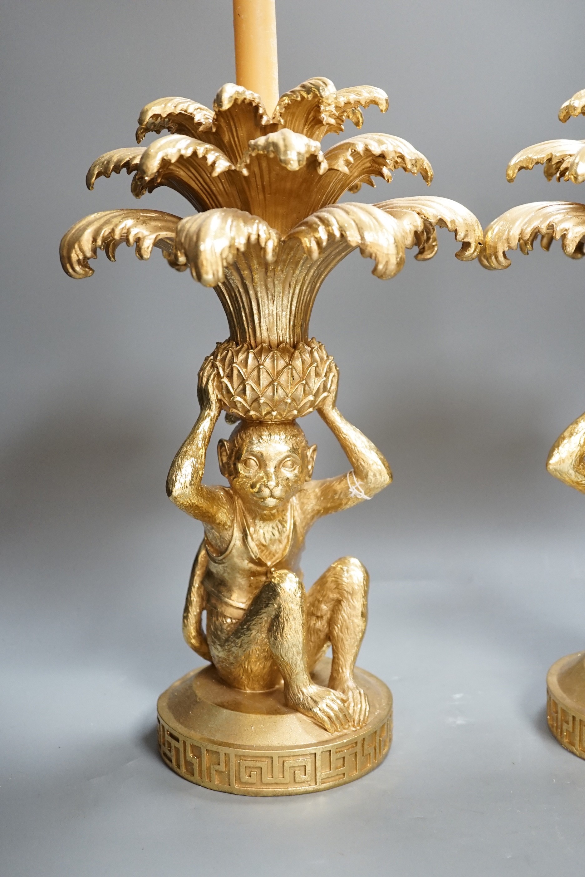 A pair of gilt resin ‘monkey and pineapple’ candlesticks. 37cm tall